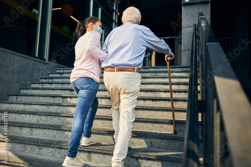 Woman assisting the senior man climbing staircase