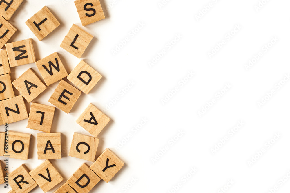 Top view of square wooden tiles with the English alphabet scattered on a white background with space for text. The concept of thinking development, grammar.