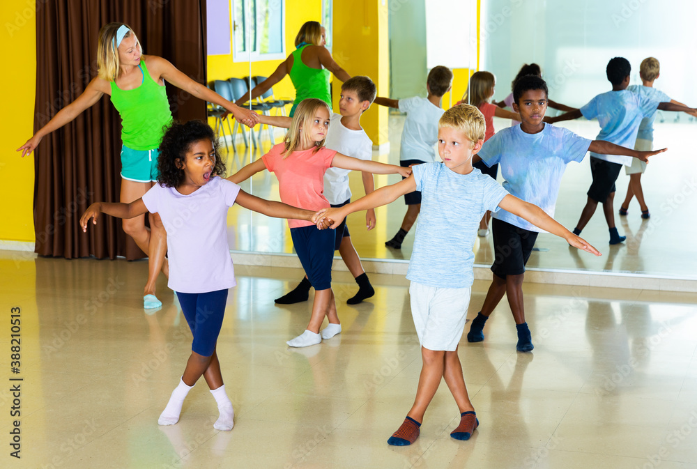 Tweenagers in pairs learning to dance active boogie-woogie with woman choreographer in modern studio