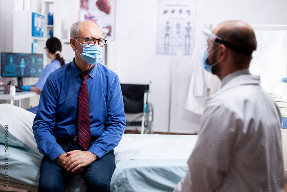 Obraz premium Doctor talking with senior woman wearing face mask about protection against coronavirus pandemic. Global health crisis, medical system during pandemic, sick elderly patient in private clinic.