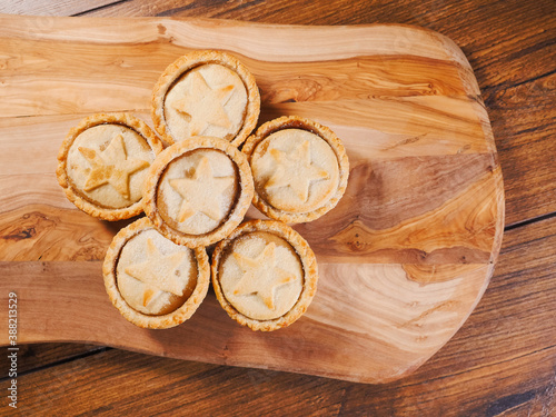 Fototapeta Naklejka Na Ścianę i Meble -  Stack of mince pies on a wooden board and table. Classic Christmas pastry product