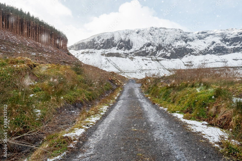 Snow flakes falling on a small asphalt road which leads into mountains covered with snow. Nobody. Gleniff Horseshoe Drive, county Sligo, Ireland Snow flakes falling on a small asphalt road which leads into mountains covered with snow. Nobody. Gleniff Horseshoe Drive, county Sligo, Ireland