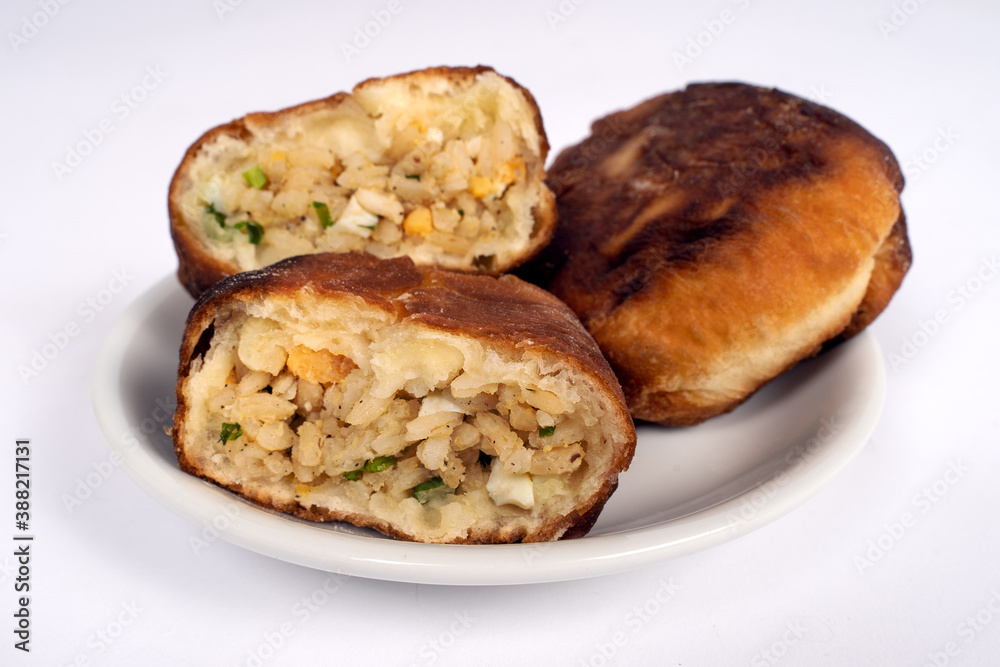 Fried homemade pies with rice, egg and herbs on little plate, white background, copy space, close up. Vegetarian food and cooking. Fried homemade pies with rice, egg and herbs on little plate, white background, copy space, close up. Vegetarian food and cooking.