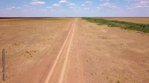 Fly over an empty dusty road via drone in desert or semi-desert region