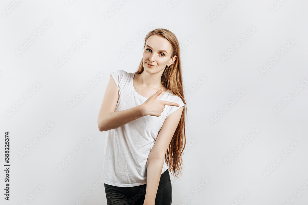 Young beautiful girl smiling and showing finger to the side on gray isolated background Young beautiful girl smiling and showing finger to the side on gray isolated background