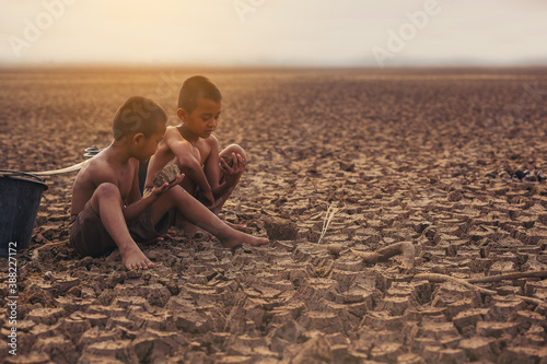 Climate change, Two Asian boys walking and searching for water on dry ground and sunset. Environment conservation and stop global warming concept