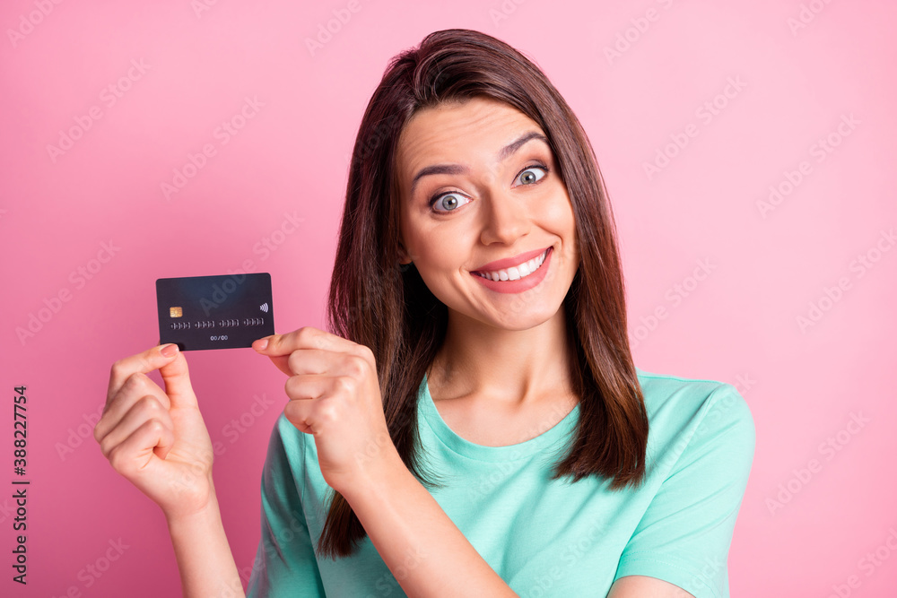 Photo portrait of woman holding credit card with fingers isolated on pastel pink colored background Photo portrait of woman holding credit card with fingers isolated on pastel pink colored background