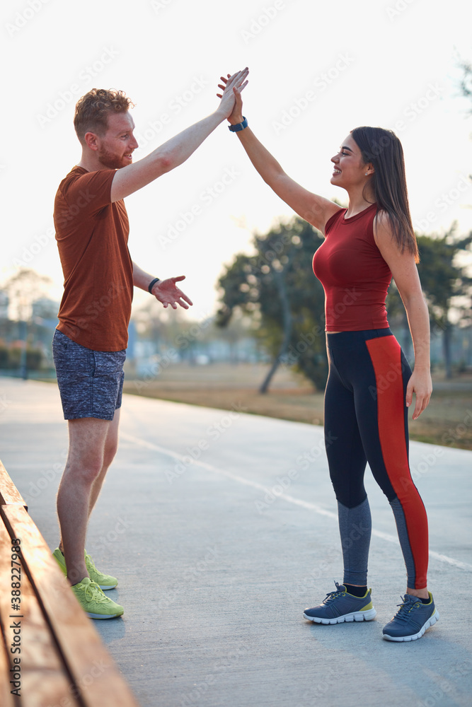 Fototapeta premium Two young sporty man and woman exercising in urban park.