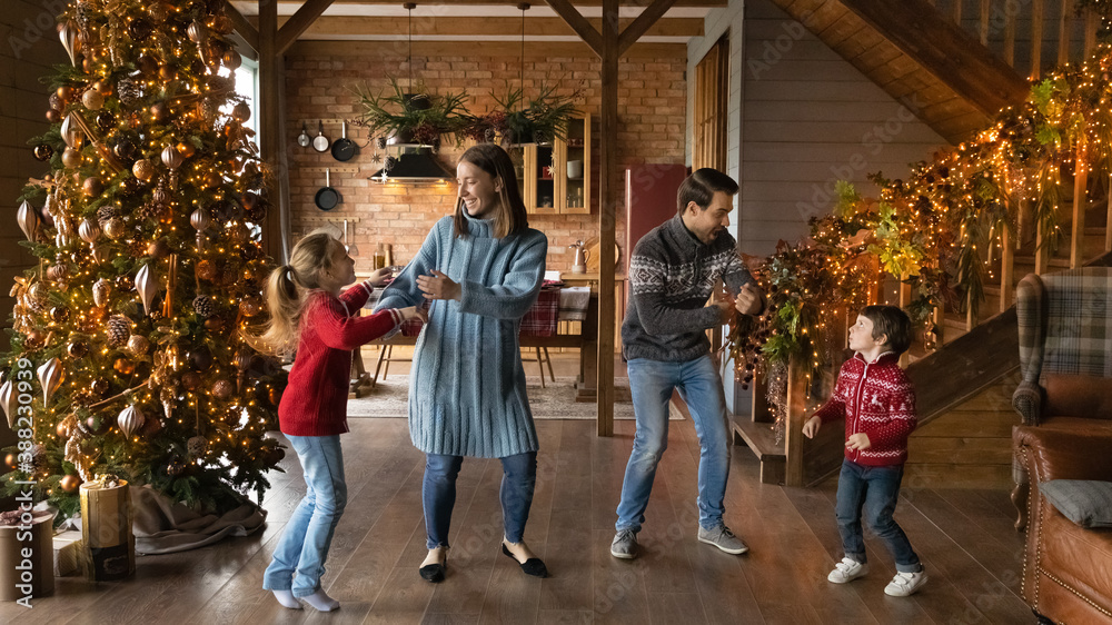 Wide banner panoramic view of happy young Caucasian family with two small kids have fun celebrating Christmas at home. Overjoyed parents with children enjoy New Year winter holidays together. Wide banner panoramic view of happy young Caucasian family with two small kids have fun celebrating Christmas at home. Overjoyed parents with children enjoy New Year winter holidays together.