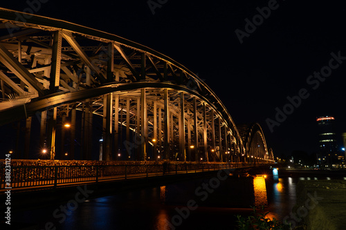 Germany, Cologne, a large bridge lit up at night © SkandaRamana