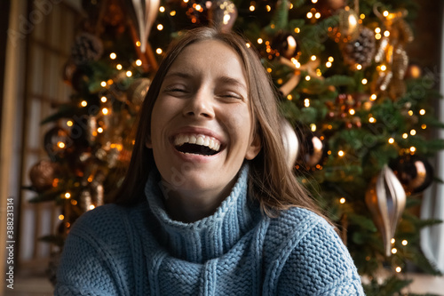 Close up portrait of overjoyed young Caucasian woman have fun laugh and joke enjoying Christmas winter holidays at home. Excited millennial female feel playful positive and joyful, celebrate New Year.