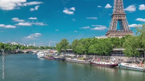 The Eiffel tower timelapse from Bir-Hakeim bridge over the river Seine in Paris. Ship and boats on river at sunny summer day photo