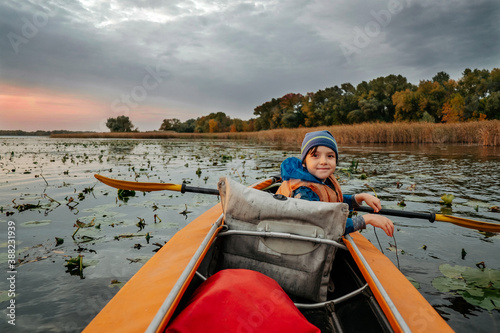 Evening kayak trip along the river in autumn. The active lifestyle of the child in the family.