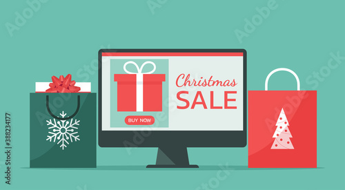 Christmas online shopping or winter holiday sale concept on a computer screen with gift box and shopping bags, vector flat illustration