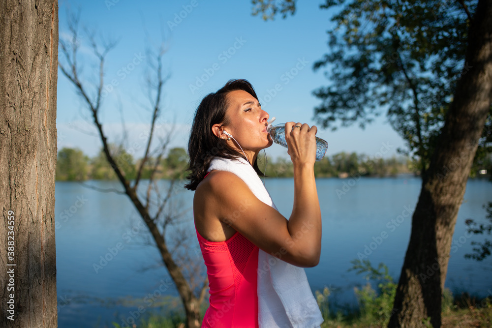 beautiful woman drinking mineral water in a bottle during running sport fitness and exercising outdoor