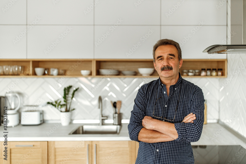 Portrait of mature man who showing his new modern kitchen.