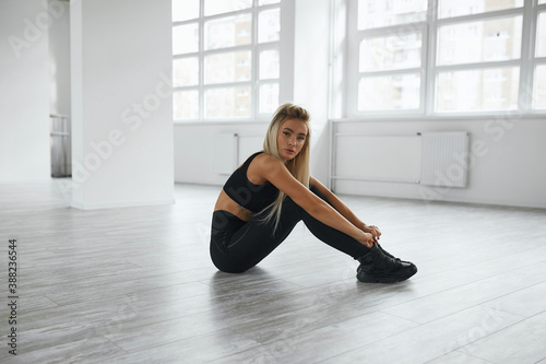 young woman  blonde  sportswoman is engaged in the gym on the mat. the girl shakes the press. the girl  lying on the floor  threw her hands behind her head. the athlete pulls the elbow to the knee