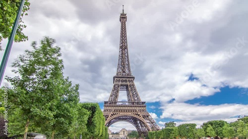 Champ de Mars and the Eiffel Tower timelapse hyperlapse in a sunny summer day. Paris, France. Green trees and cloudy sky, people walking around photo