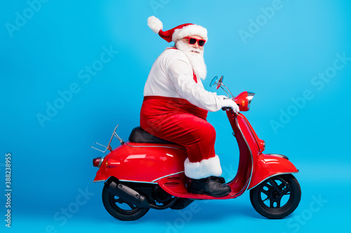 Full size profile side photo of stylish santa claus with big belly beard drive motor bike x-mas christmas dream present delivery wear suspenders overalls isolated blue color background