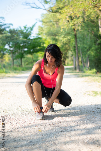 beautiful woman tying her shoelace during running sport fitness and exercising outdoor in a countryside park