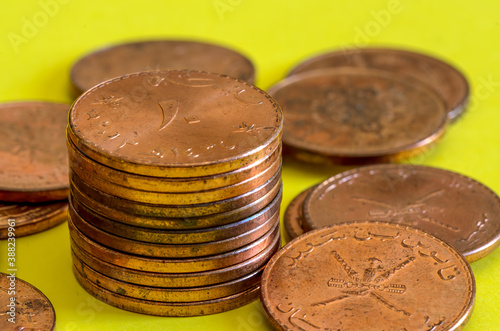 Pile of Omani 10 baiza bronze coins on a yellow background photo