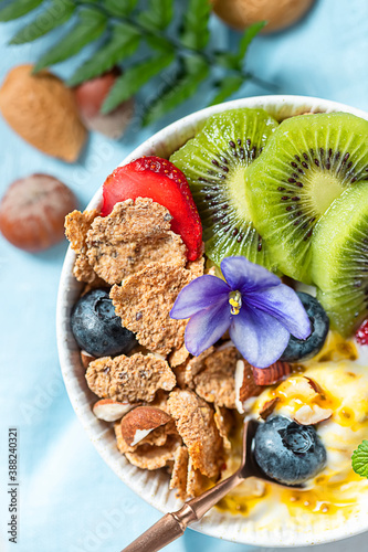 Breakfast with fresh Greek yogurt, strawberries, kiwi and granola on a light concrete background. Healthy food nutrition, snack or breakfast.