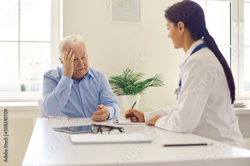 Senior man patient complaining on headache to young positive woman doctor
