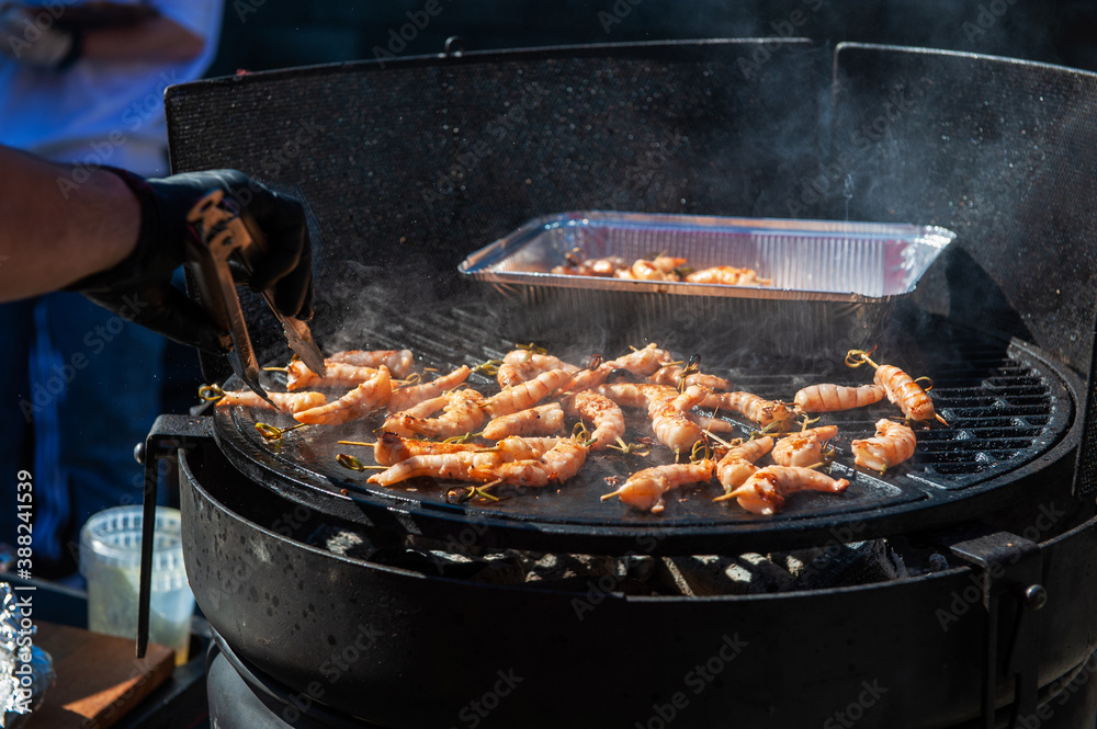 A professional cook prepares shrimps on the grill outdoor, food or catering concept A professional cook prepares shrimps on the grill outdoor, food or catering concept