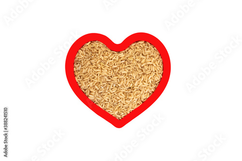 Brown rice groats in heart shape red frame isolated on white.