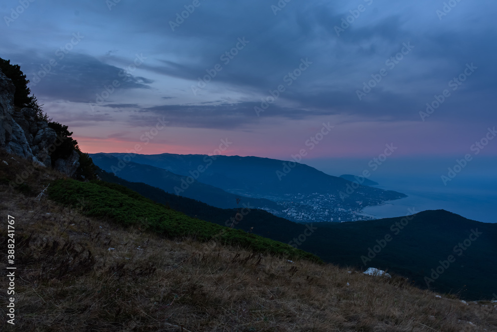 Fantastically beautiful sunset over Yalta from AI-Petri mountain. Autumn mountain landscape. Blue and pink shades of clouds. A popular tourist destination. Cloudy evening post-sunset landscape.