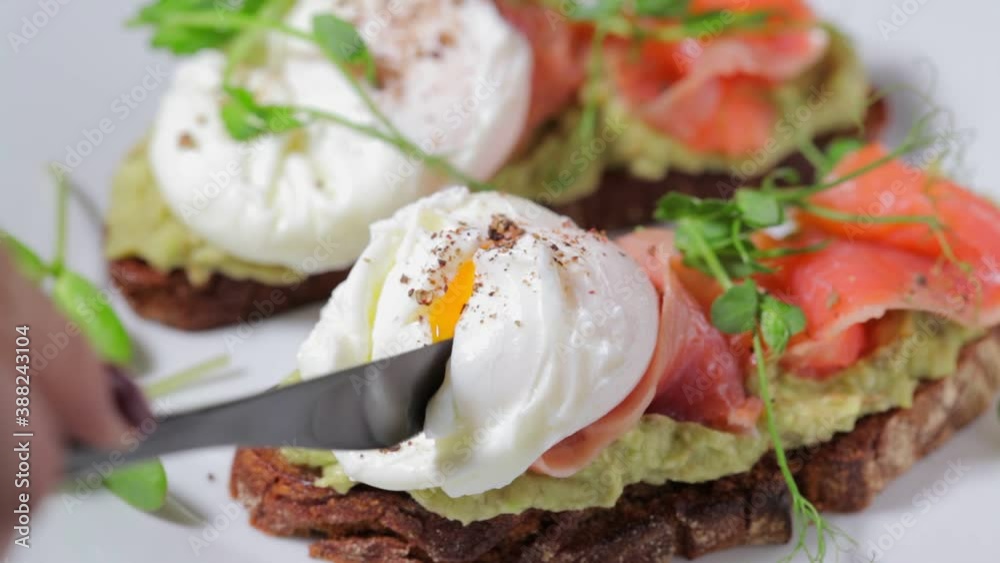 Toast with salmon, poached egg and avocado on white plate. Poached egg with salmon and guacamole on rye bread. Toast with salmon, poached egg and avocado on white plate. Poached egg with salmon and guacamole on rye bread.