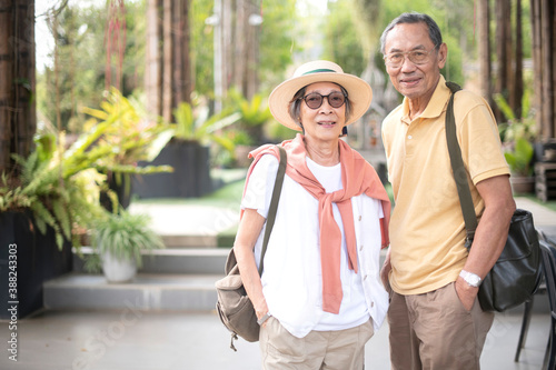 Asian old couple traveler enjoy happy time together while sightseeing in flower garden or public park in summer time. Healthy and positive retirement people lifestyle