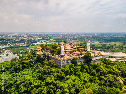 Aerial view of bodhisattva architecture and double sky dragon in Chau Thoi pagoda, Binh Duong province, Vietnam in the afternoon with sun through cloud create auspicious buddha. © CravenA