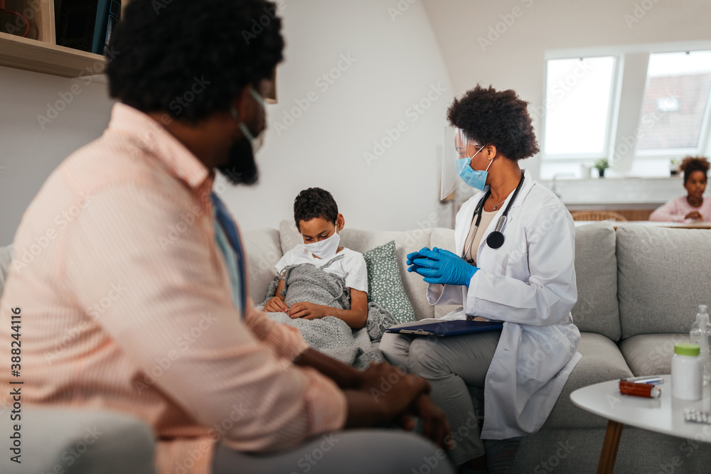 Fototapeta premium Female doctor visiting father and son at home