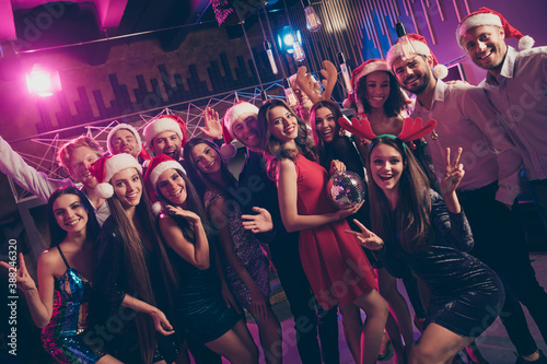 Group photo portrait of people posing making v-signs holding disco ball wearing christmas hats