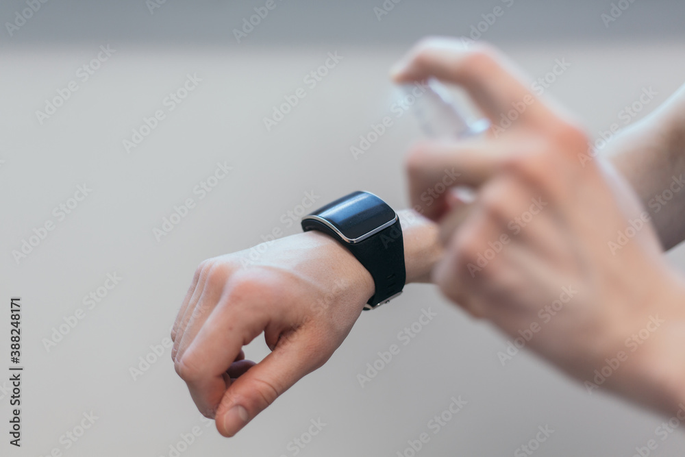 Fototapeta premium casual man spraying alcohol antiseptic on his smart watch.