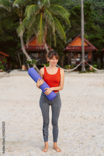Obraz na płótnie Full length portrait of a smiling sports woman with yoga mat walking w salonie