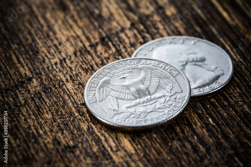 Detailed close-up of many shiny american quarter coins on grungy wooden background. Selective focus, shallow depth of field.