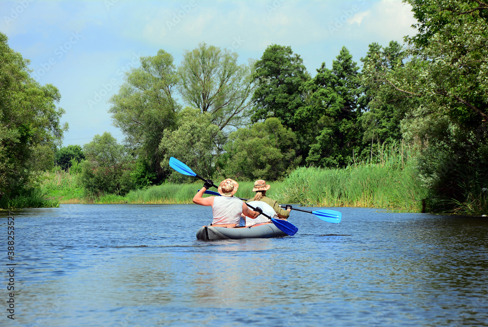 Two people on a canoe with oars floating on the river.