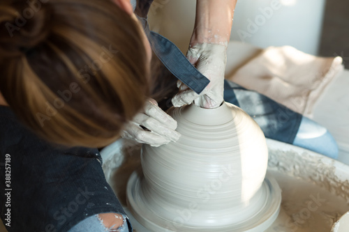 master works pottery wheel. woman make ceramic vase by hand from wet clay