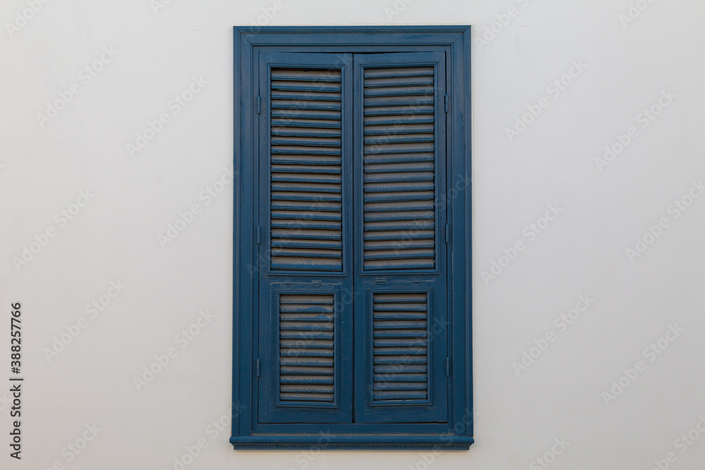 Closed blue window on light wall