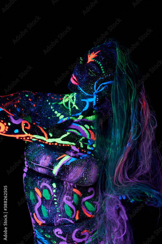 Fototapeta premium Art woman body art on the body dancing in ultraviolet light. Bright abstract drawings on the woman body neon color. Colored hair and face