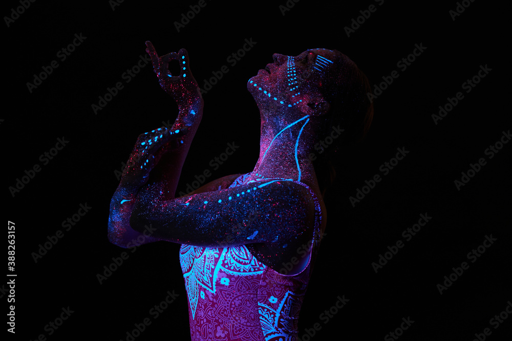Art woman cosmos in ultraviolet light. Entire body is covered with colored droplets. Girl posing in the dark. Noise, out of focus - obrazy, fototapety, plakaty 