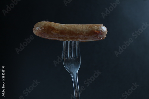 sausage sausage fried impaled on a fork on a black background copy space