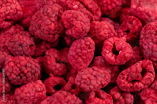 Fototapeta Naklejka Na Ścianę i Meble -  Macro shot of freeze dried organic raspberries, fruit snack, ingredient for smoothies, sauces, baked treats. Red berries background. Healthy food, fresh fruits, mindful eating concept, text space