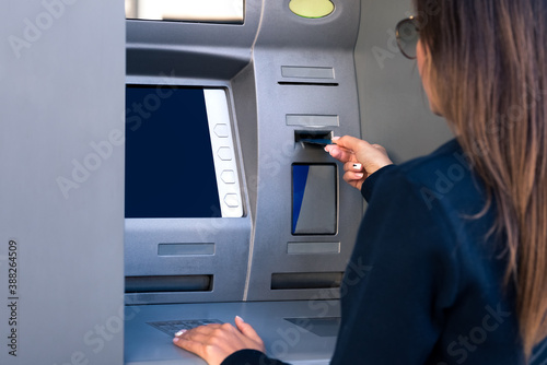 Woman using an ATM machine. Withdrawing cash money from credit or debit card at bank machine.