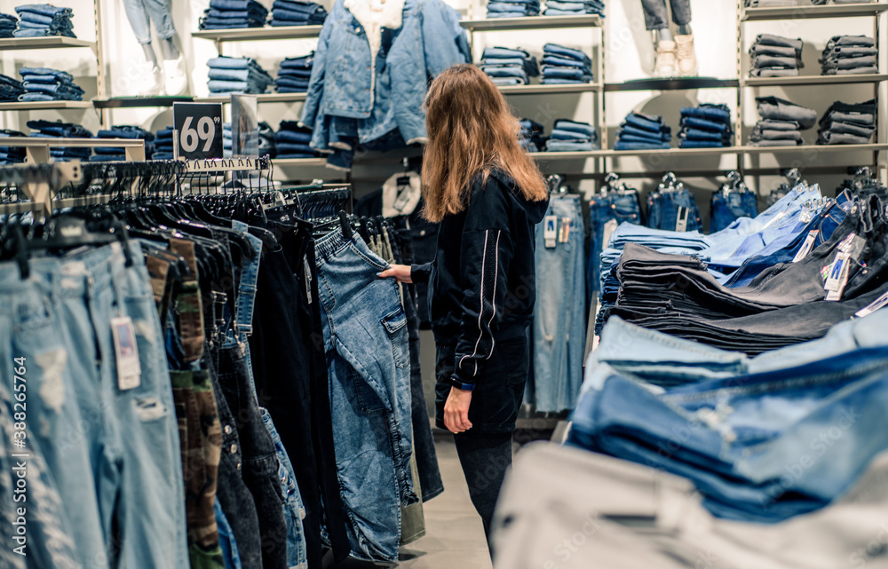 Smiling girl shopper choosing new jeans at store Smiling girl shopper choosing new jeans at store