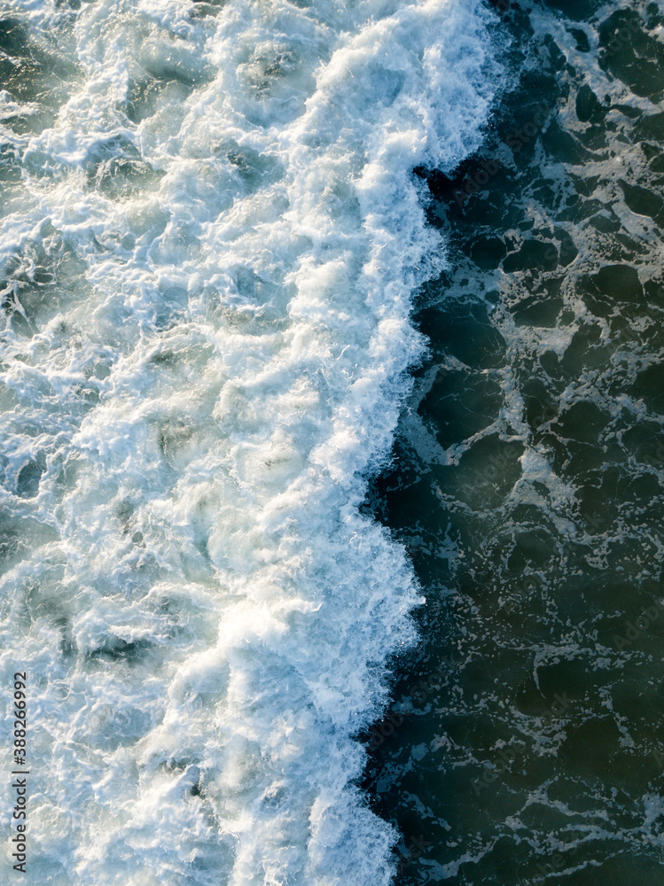 Aerial top down view of foaming waves in sea, ocean. Summer vacation, water surface, scenic seascape. Natural background texture wallpaper