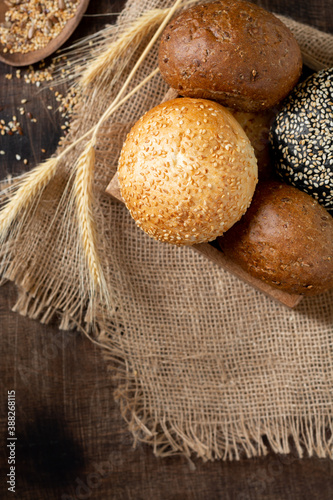 Sesame buns for burgers. Buns in a wooden box on a brown wooden table. Homemade buns with sesame seeds. Baking close-up. Top view from the copyspace	
