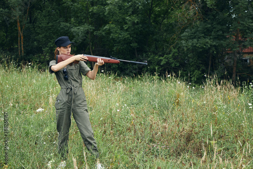 Woman soldier He is holding a gun in a green hunting overalls fresh air 
